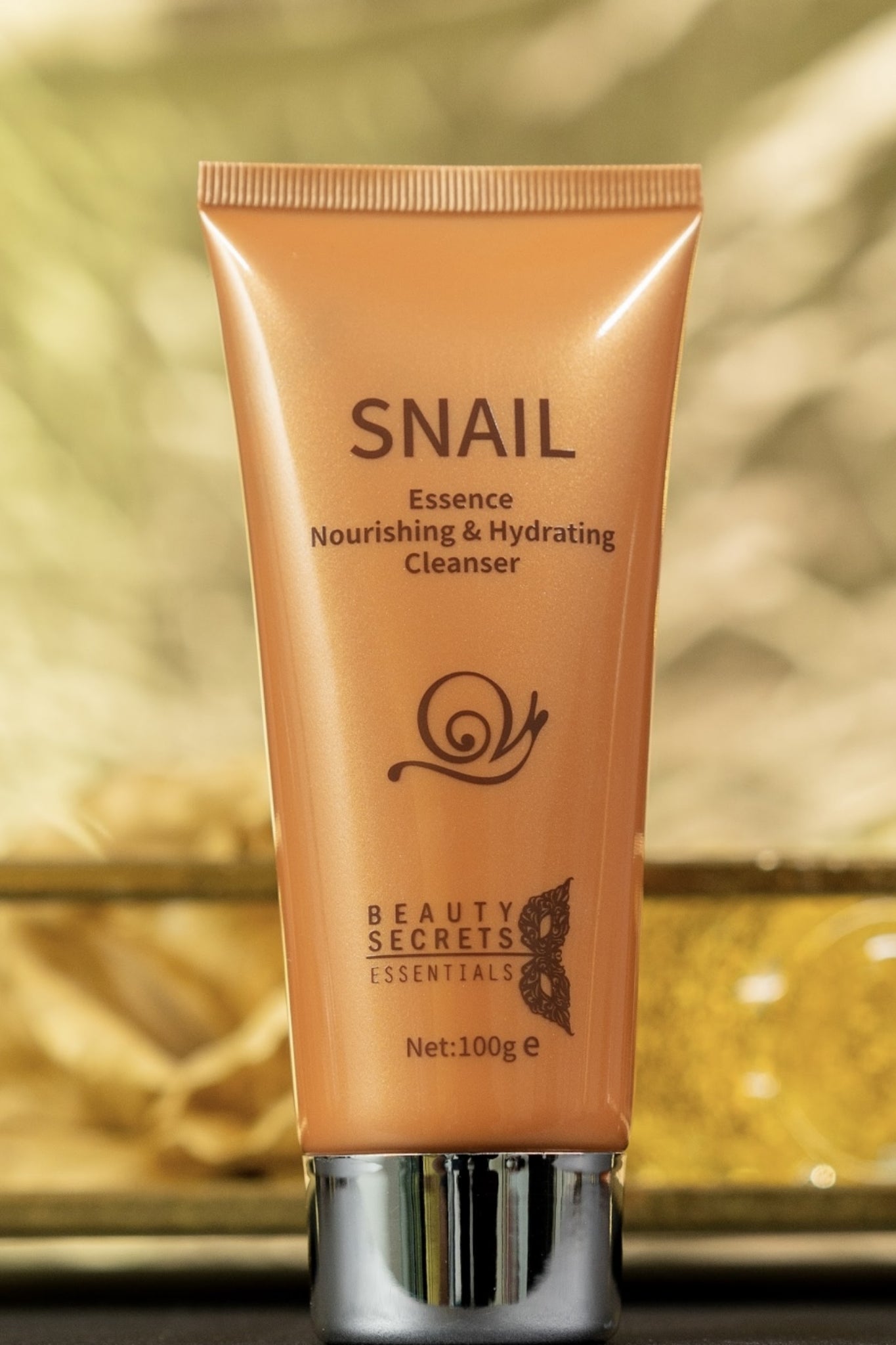 Nourishing and hydrating essence in gold tube with silver cap that cleans and moisturise the skin in gold background.