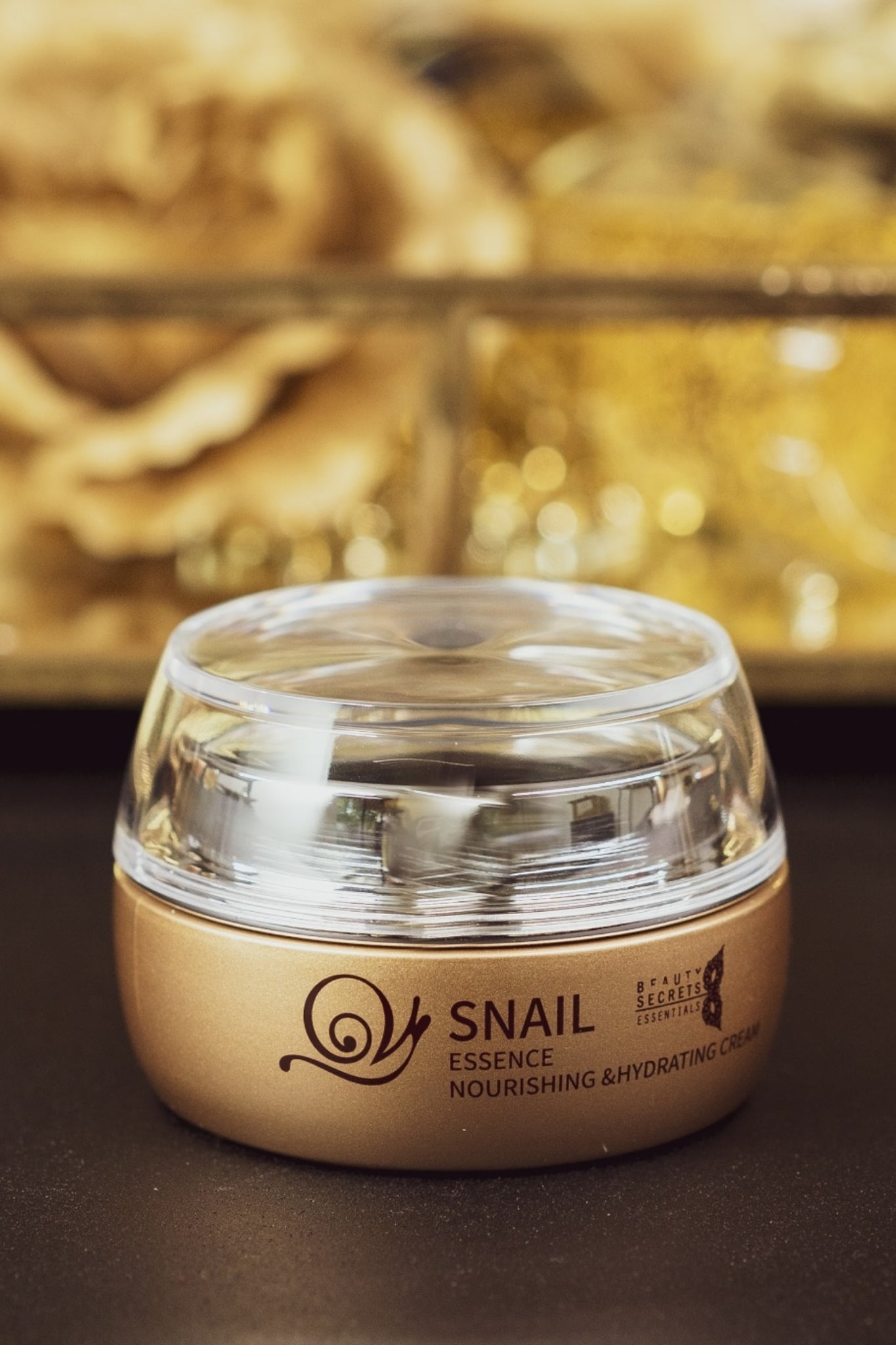 Gold jar with transparent lid of hydrating cream that makes skin smooth in rich and gold luxurious background.
